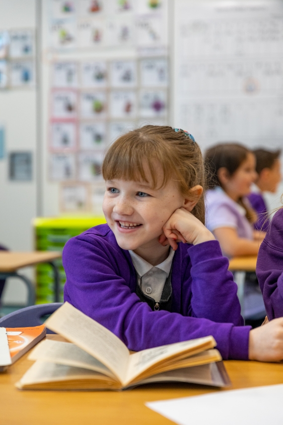 photograph of a smilin girl with an open book